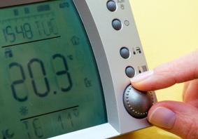 This is a close up image of fingers adjusting a domestic thermostat to a high temperature.