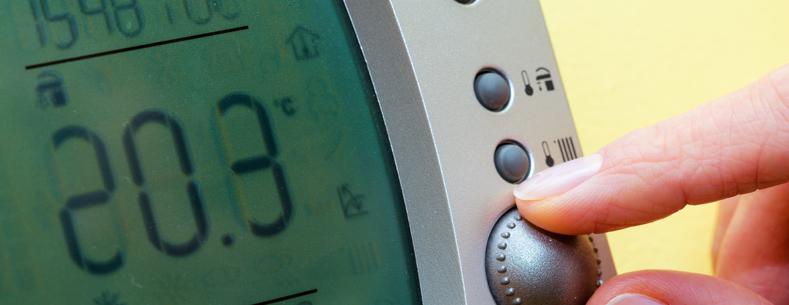 This is a close up image of fingers adjusting a domestic thermostat to a high temperature.