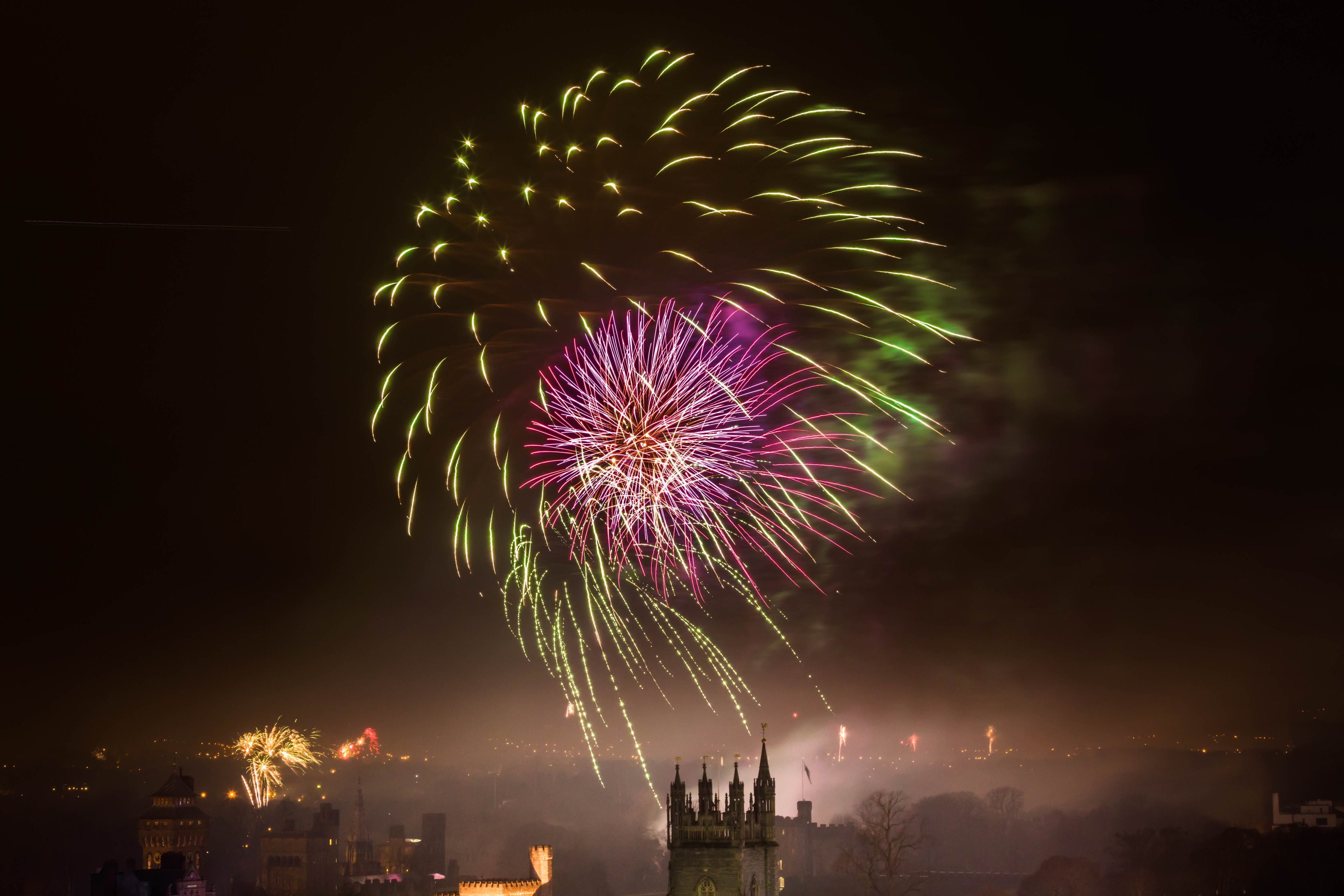 a large firework explodes over the Cardiff skyline, smaller fireworks explode in the distance