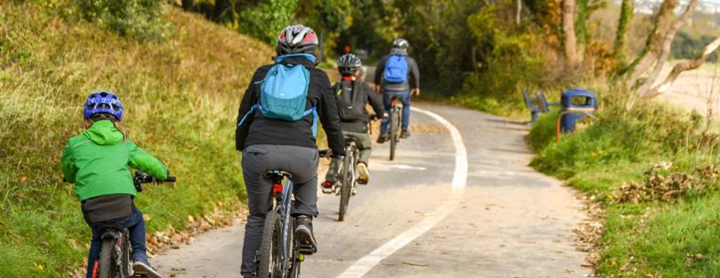Adults and children cycling on the Wales Coastal Path in Swansea