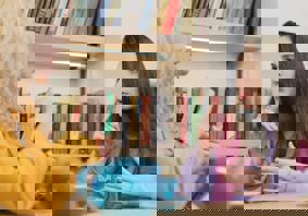 Two women sit at a table with a pot of tea, having a conversation in sign language.