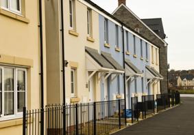 Row of newly built terraced houses with cream and blue walls, small porches, and black railings along the front
