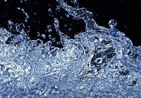 Close-up of splashing water with droplets frozen in motion against a dark background.