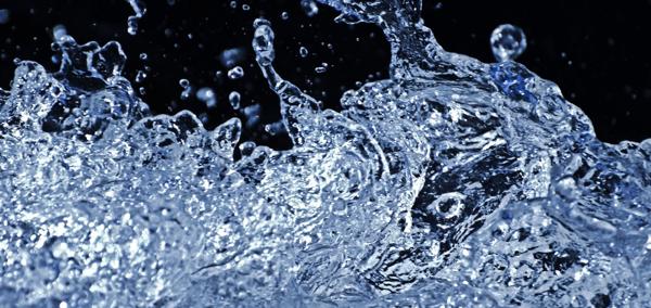 Close-up of splashing water with droplets frozen in motion against a dark background.