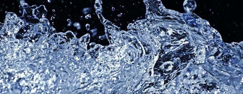 Close-up of splashing water with droplets frozen in motion against a dark background.
