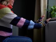 Picture of a woman putting her hands on a radiator for warmth.