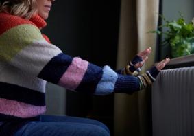 Picture of a woman putting her hands on a radiator for warmth.