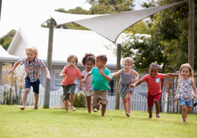 A group of small children running on grass. 