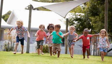 A group of small children running on grass. 