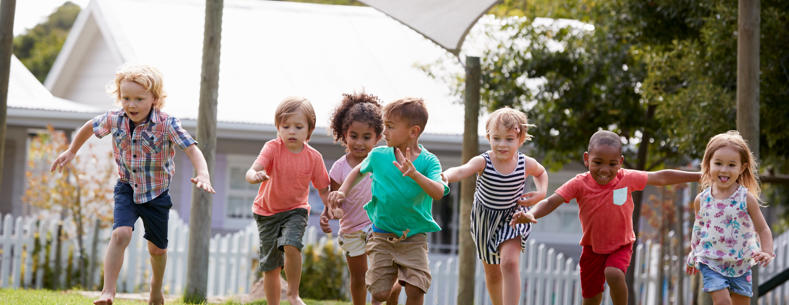 A group of small children running on grass. 