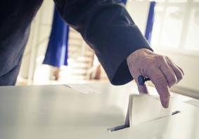 An image of a person placing a piece of paper in a ballot box.