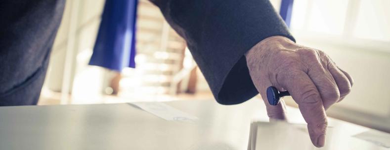 An image of a person placing a piece of paper in a ballot box.