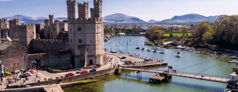 Aerial image of Caernarfon Castle from across the river on a sunny day