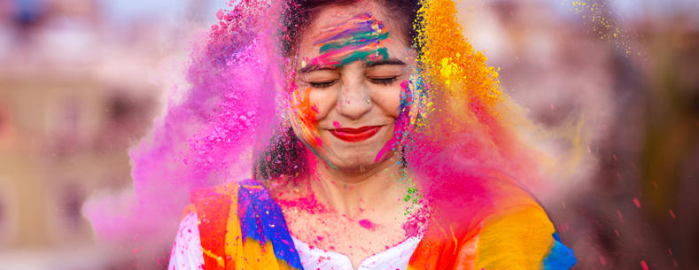 The article’s main image is of a happy person celebrating the Indian festival of Holi with coloured powders.