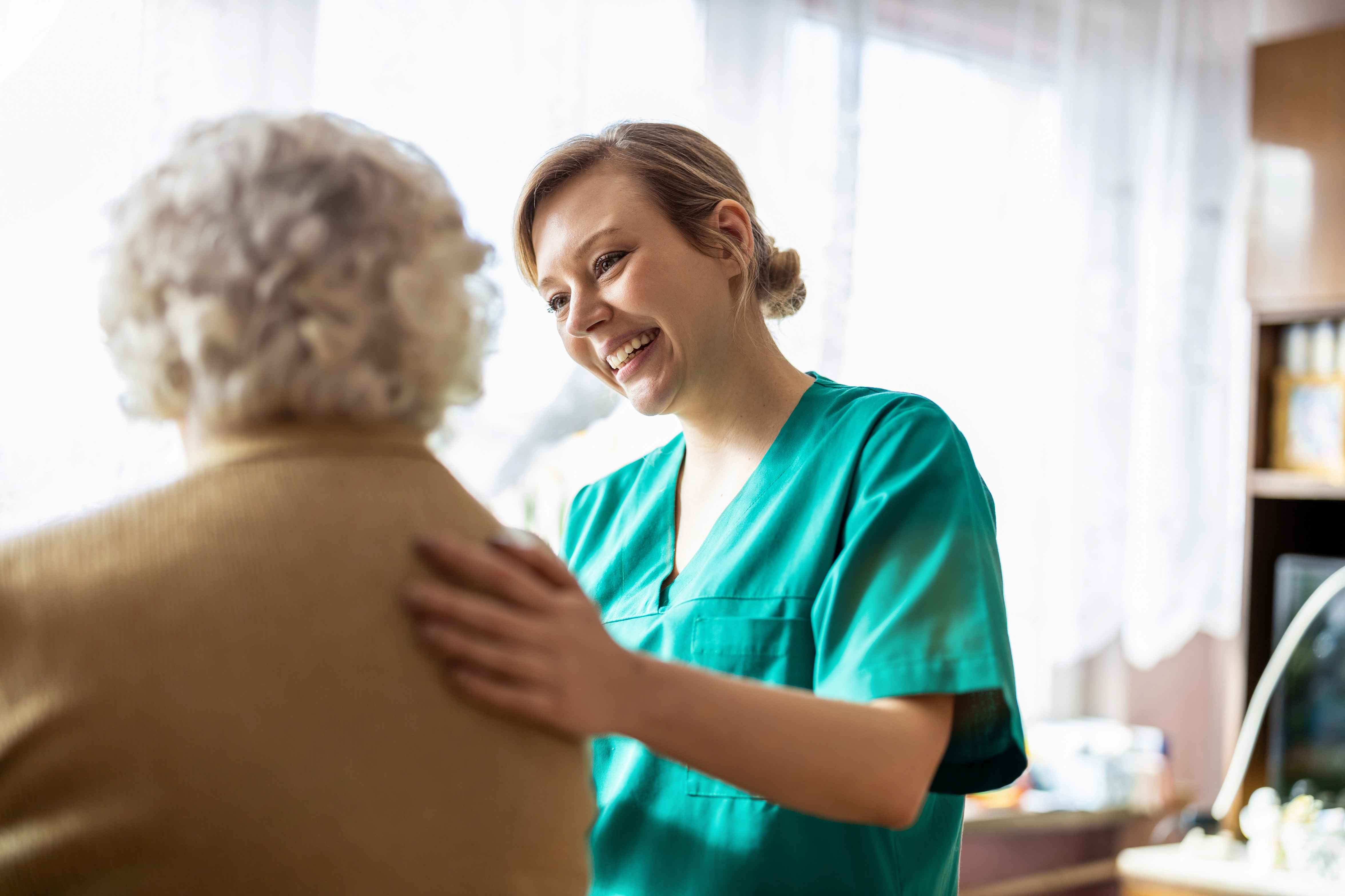 Healthcare worker speaking with an older person in a care setting.