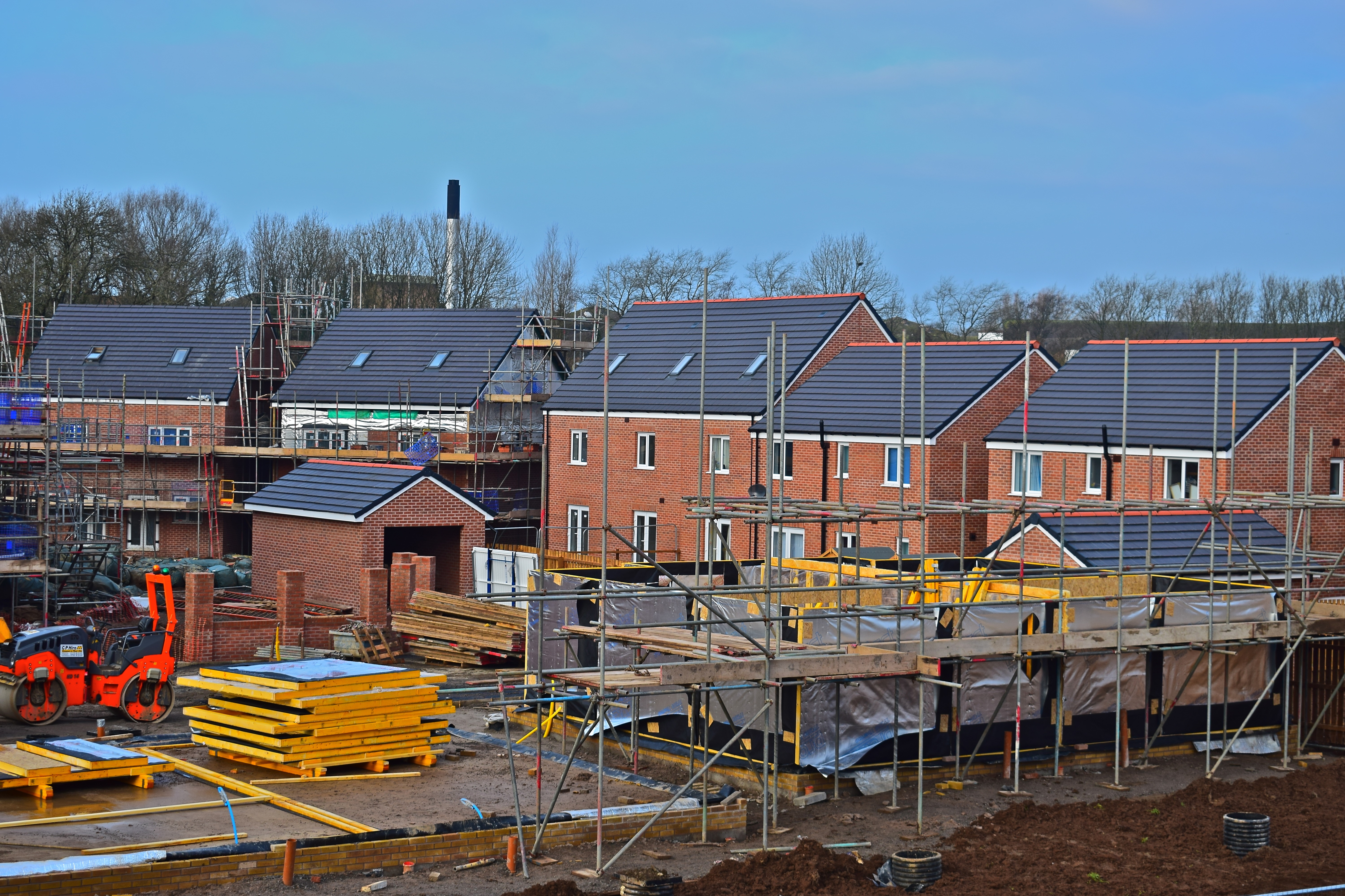 This is an image of a housing construction site with houses at various stages of completion.