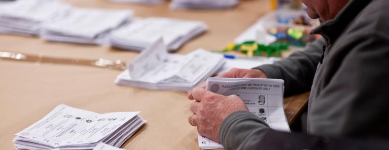 An image of someone counting votes at a Senedd election. 