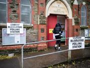 A person in a black coat walking into a polling station.