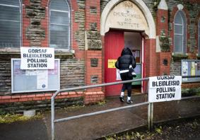 A person in a black coat walking into a polling station.
