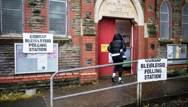 A person in a black coat walking into a polling station.