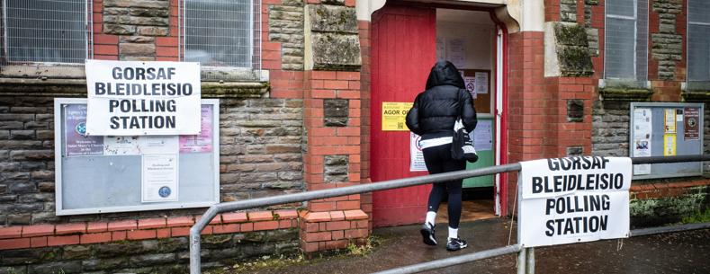 A person in a black coat walking into a polling station.