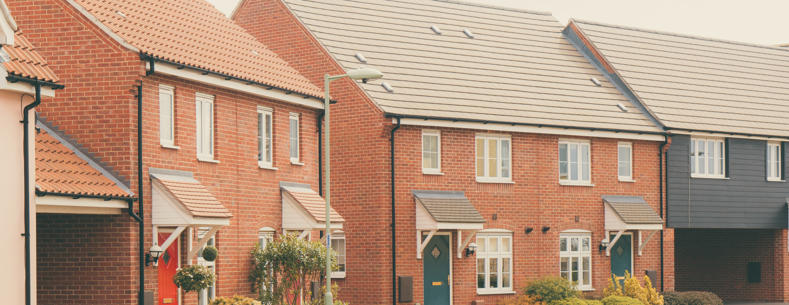 A row of new build red-brick houses. Some greenery to the frontages