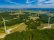 Cover image: A high angle landscape photograph of wind turbines and woodland on a hillside. 