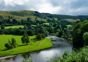 Image of river bend in a Welsh farming landscape, with hilltop quarry in the distance.