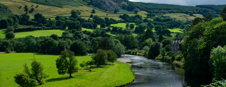 Image of river bend in a Welsh farming landscape, with hilltop quarry in the distance.