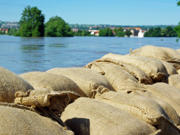 A photograph of sandbags in front of a flooded river.