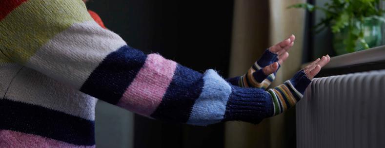 Woman warming her hands by the radiator