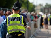 A uniformed police officer wearing a high-visibility yellow vest, standing outdoors, symbolising frontline policing and public visibility.